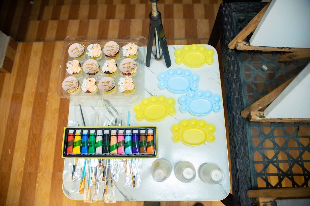 Cupcakes, paint, brushes, and plates arranged on a table.